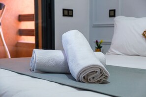 Letto rifatto con asciugamani bianchi arrotolati e copripiumino verde in una camera d'albergo.