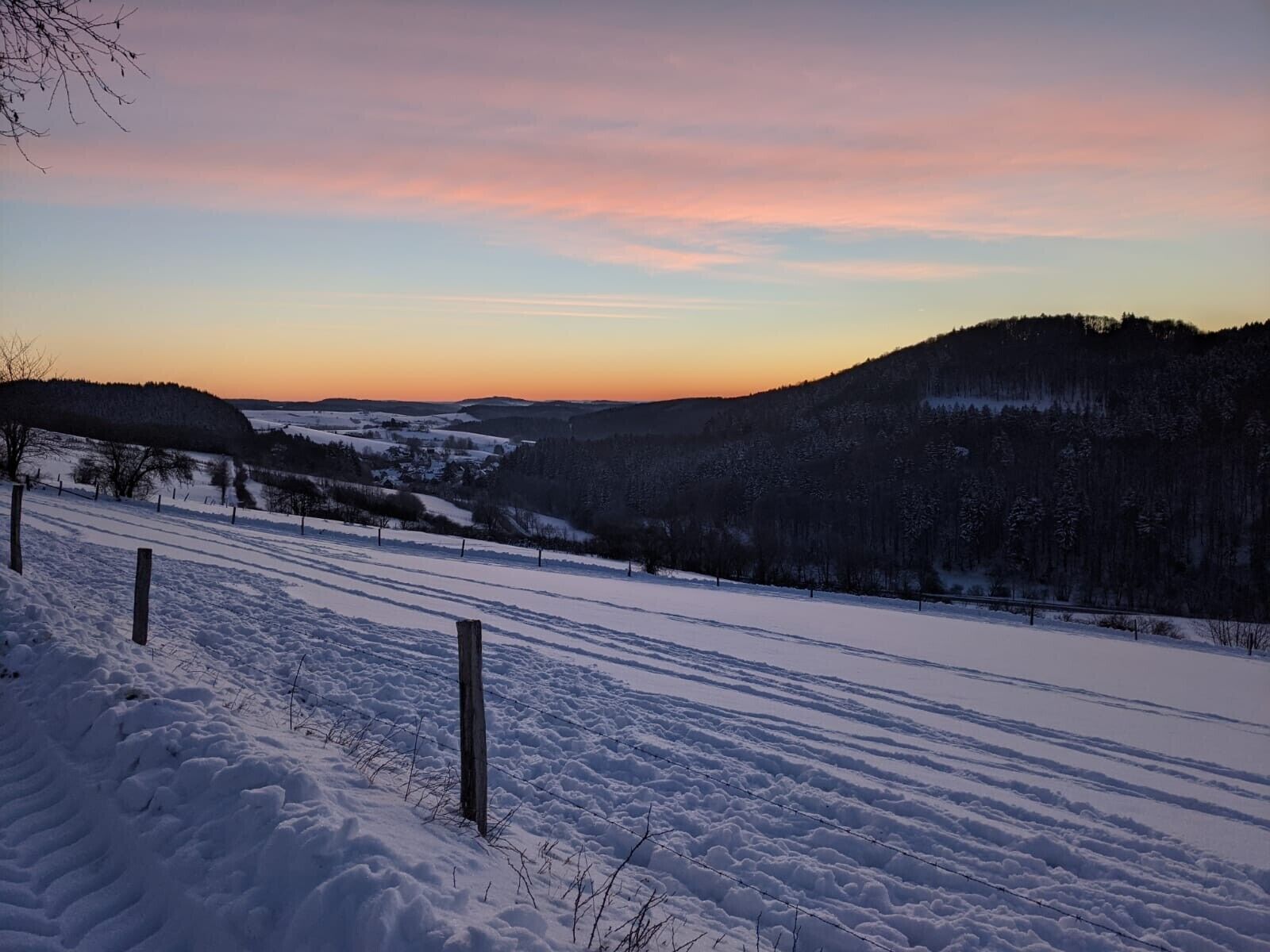 Un paysage enneigé avec une clôture et une colline en arrière-plan.
