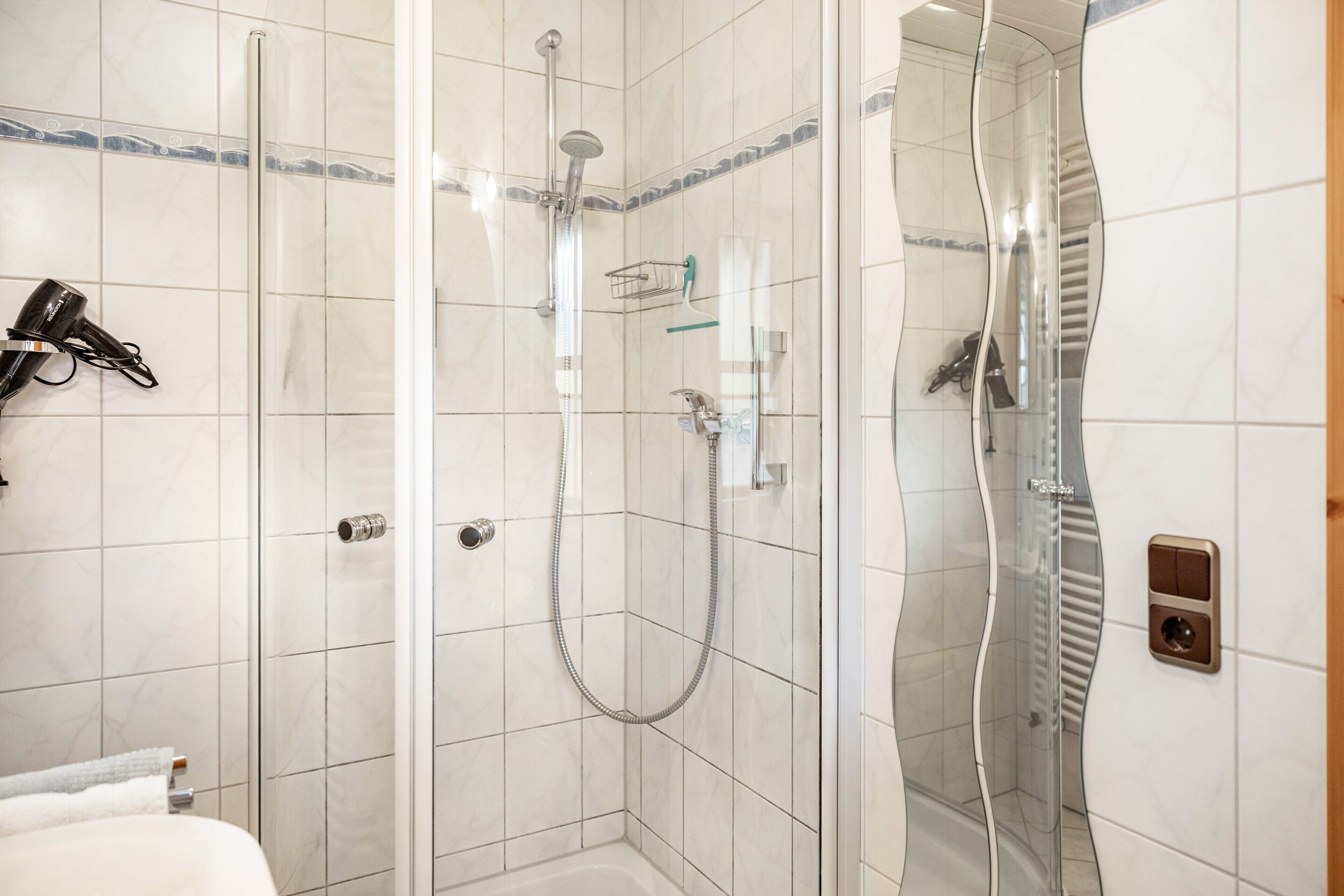 A bathroom with a shower, a towel rack, and a toilet.