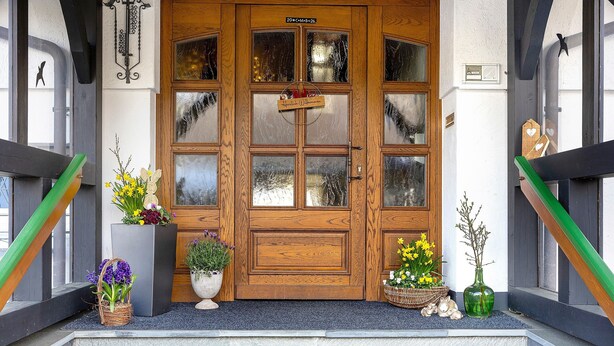 A wooden double door with glass panels, a welcome sign, and potted plants on the steps. - Lauras Country Guesthouse 'Type B Double Room with Balcony' (Medebach)