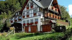 Ein traditionelles Fachwerkhäuschen mit vielen Fenstern, einem Balkon mit Blumenkästen und einer Garage.