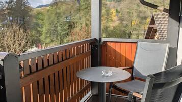 Een overdekt terras met een tafel en stoelen, met uitzicht op een glooiend landschap.