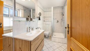 Ein modernes Badezimmer mit einem Holzkosmetikschrank, einer Duschkabine aus Glas und einer Toilette.