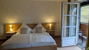 A bedroom with a bed, two bedside tables with lamps, a sliding glass door to a balcony, and a carpeted floor. - Laura's Country Guesthouse 'Type D Comfort Double Room with Balcony' (Medebach)