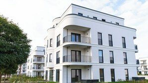 A modern multi-story residential building with balconies, large windows, and a well-maintained lawn. - Penthouse Premium Spa H7 - Holiday Flat at Yachthafen Barth (Barth)