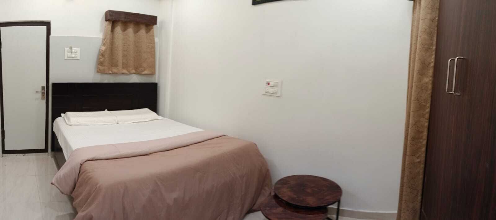 Un dormitorio con cama, una mesita redonda, un armario y una puerta.