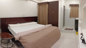 A bedroom with a bed, a wardrobe, a small stool, and a shower area. - BVR Dazzle Residency (Avanigadda)