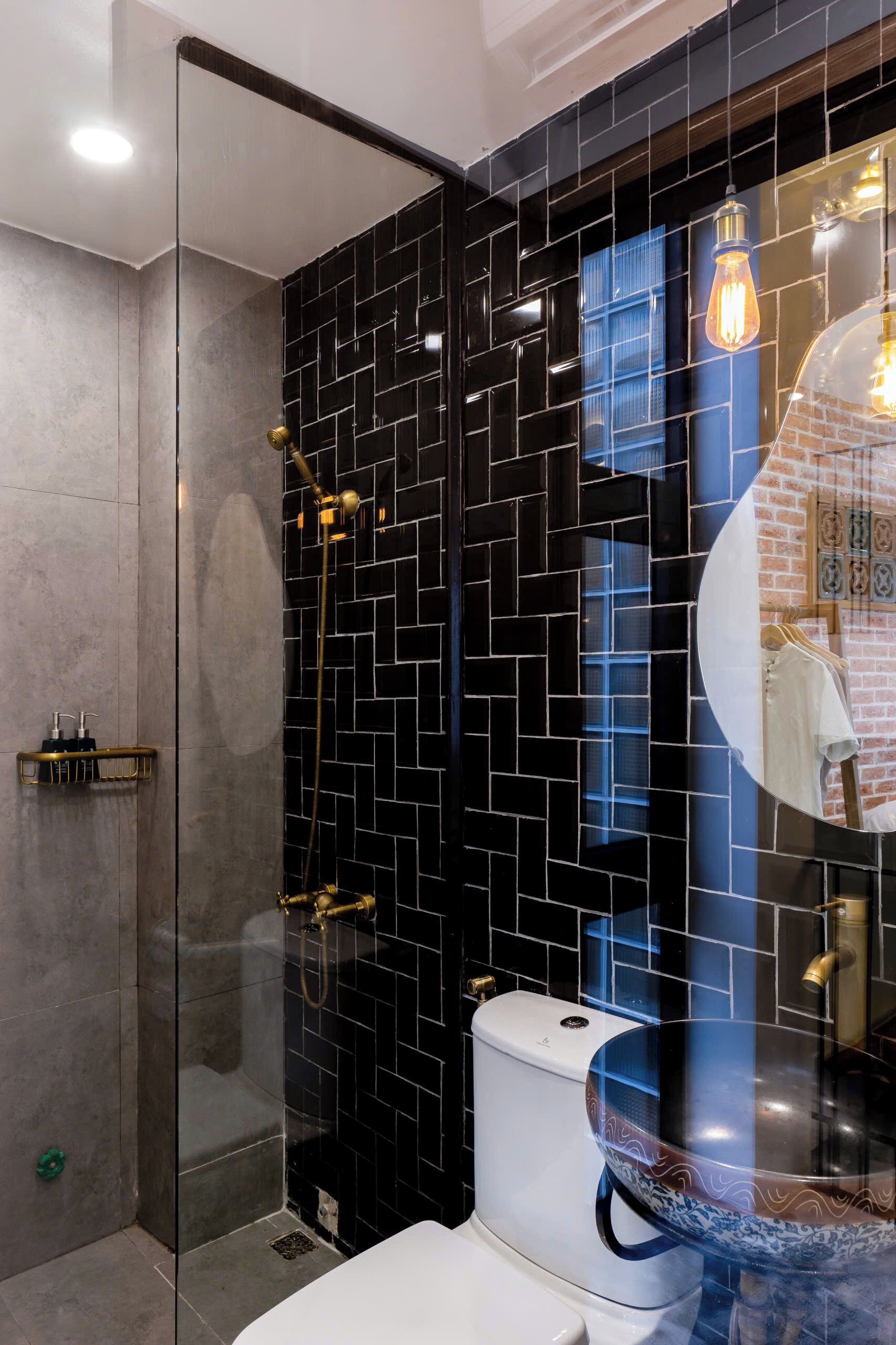 Ein modernes Badezimmer mit schwarzer Fliesenwand, einer Duschkabine aus Glas und einer weißen Toilette.