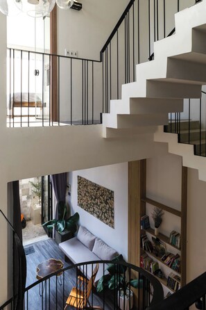A modern interior with a staircase, a sofa, a bookshelf, and a dining area. - Dakar Homestay Hue (Hue)