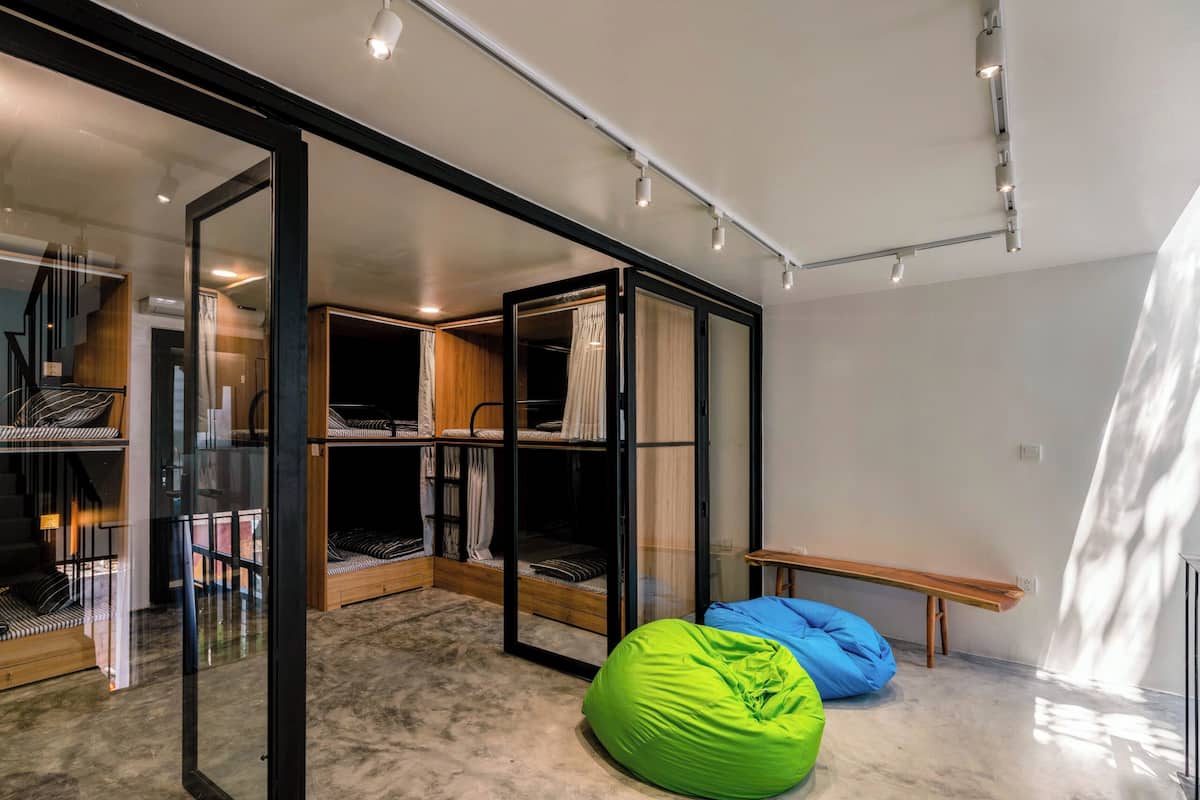 A modern room with bunk beds, a bean bag, a bench, and a glass partition.