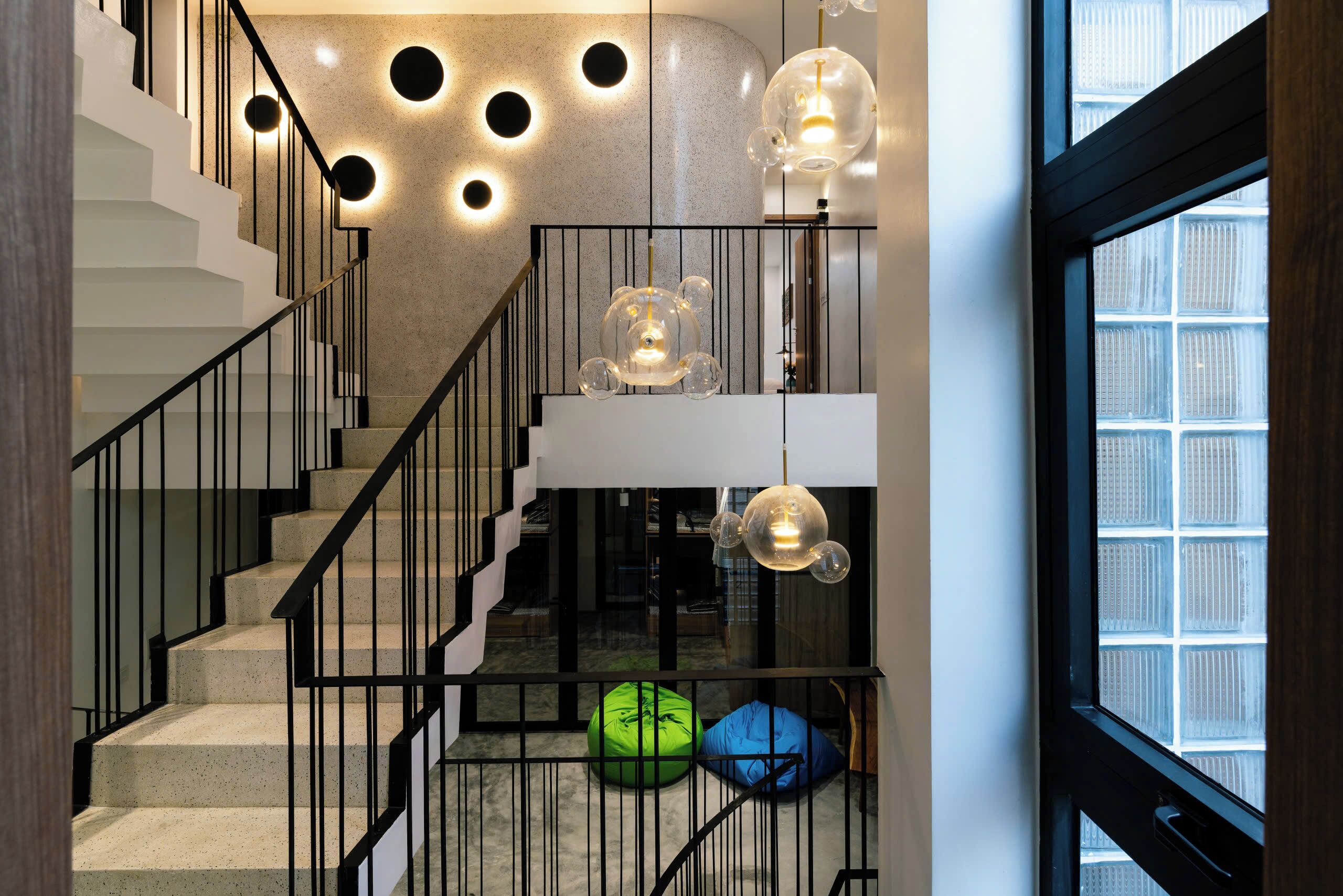 A staircase with black railings, a glass balustrade, and a modern light fixture.