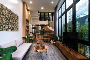A modern interior with a wooden bench, a sofa, and a TV on a wooden stand. - Dakar Homestay Hue (Hue)