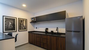 Een moderne keuken met een ingebouwde magnetron, een roestvrijstalen koelkast en donkerhouten kastjes.