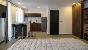 Een moderne hotelkamer met een groot bed, een kitchenette, een bar en een kledingkast.