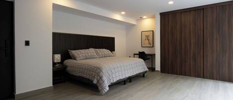 Un dormitorio moderno con una cama, mesita de noche y un panel de pared de madera.