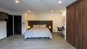 Un dormitorio moderno con una cama grande, lámparas de noche, un escritorio y un armario.
