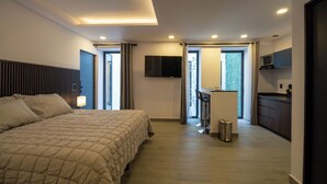 A modern hotel room with a large bed, a desk with a chair, a TV, and a view of the outdoors. - Luxurious Room in Heart of Ciudad de México - Room J1 (Mexico City)