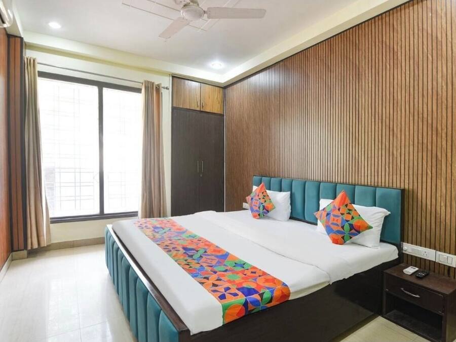 Una habitación de hotel con una cama grande, una mesita de noche, un armario y un ventilador de techo.