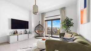 Ein modernes Wohnzimmer mit Sofa, Hängesessel, Fernseher und einem Balkon mit Blick.