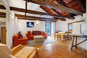 A spacious living area with a wooden ceiling, a sofa set, a dining table, and a television. - Holiday Home 'Cozy Country Loft Oleandro' with Private Terrace, Wi-Fi and Air Conditioning (Chioggia)