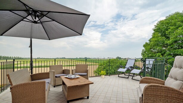 Une terrasse avec des meubles en osier, une table et un parasol.