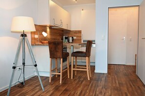 Cocina pequeña con encimeras de madera, cafetera y dos taburetes de bar.