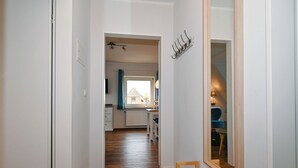 A hallway with wooden flooring, white walls, a mirror, and a coat rack. - Vacation home Cumulus - Apartment 4 (Büsum)