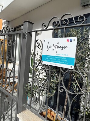 A gated entrance with a sign for 'La Maison Appartement' including contact information and a website. - La Maison Appartement - 200m from the port (Civitavecchia)
