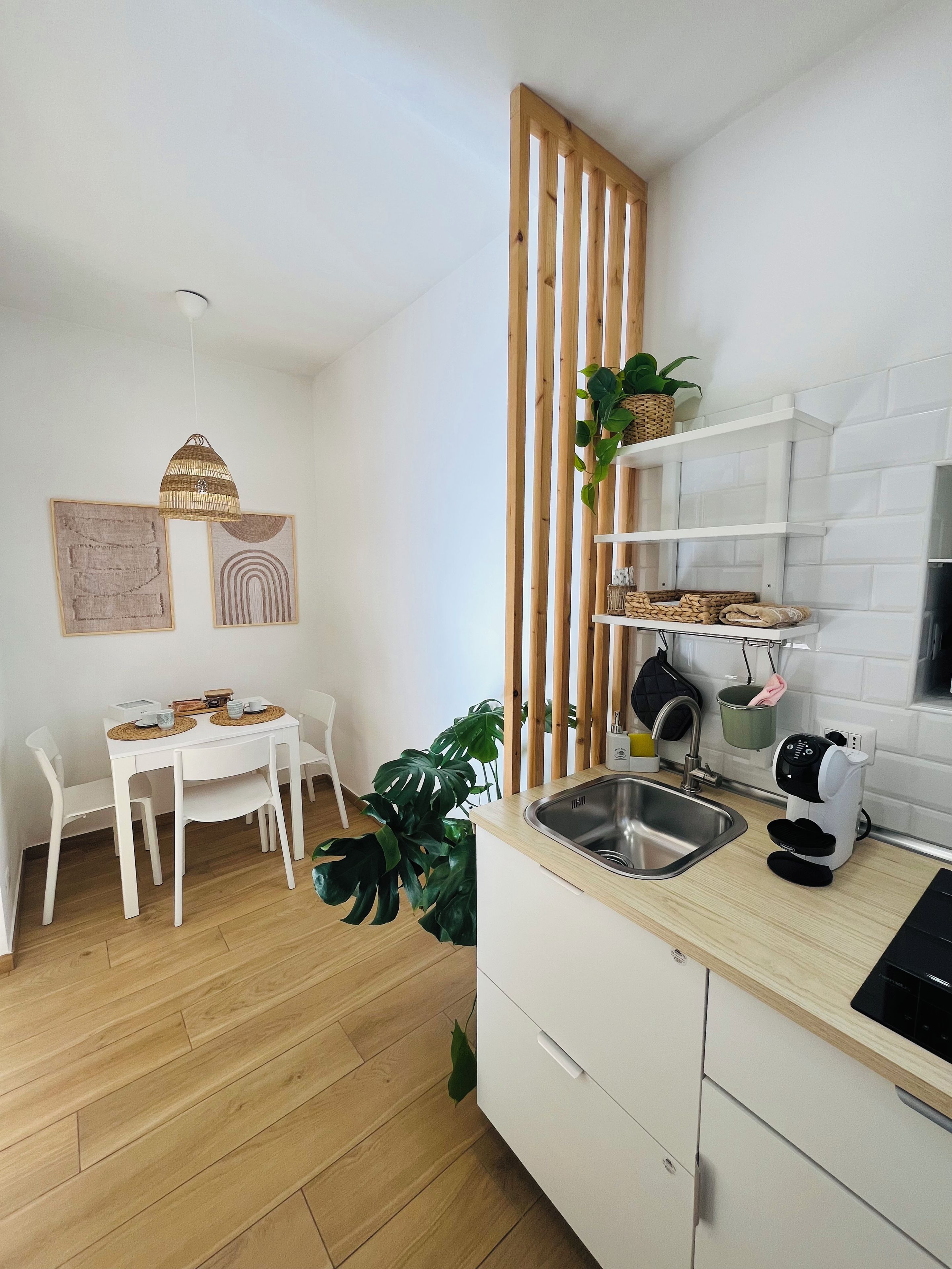 Una cucina moderna con tavolo da pranzo in legno, mobili bianchi e lavello incassato.
