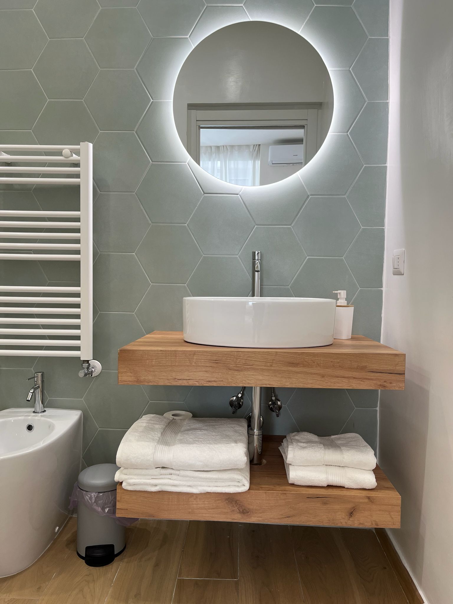 A modern bathroom with a white sink, a mirror, and a towel rack.