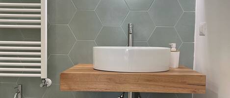 A modern bathroom with a white sink, a mirror, and a towel rack.