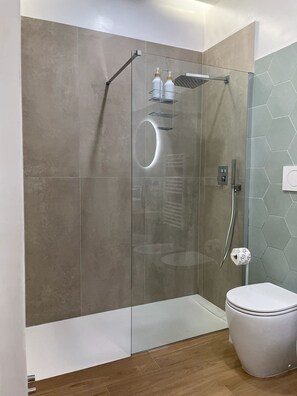 Ein modernes Badezimmer mit einer Glasduschkabine, einer Toilette und einem Waschtisch mit Spiegel.