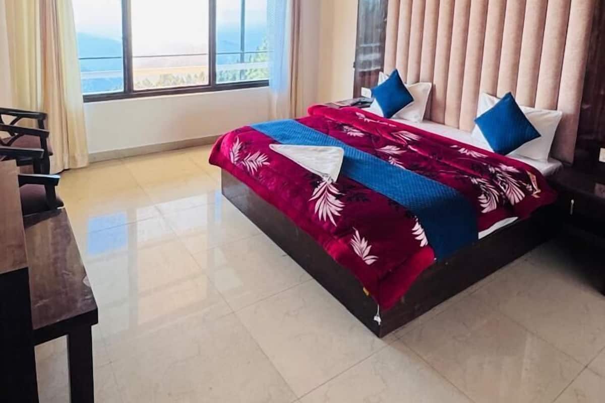 Una camera spaziosa con un letto grande, un ventilatore a soffitto e vista sull'esterno attraverso un'ampia finestra.