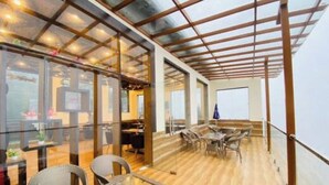 Un espace de restauration intérieur avec des cloisons en verre, des meubles en osier et un plancher en bois.