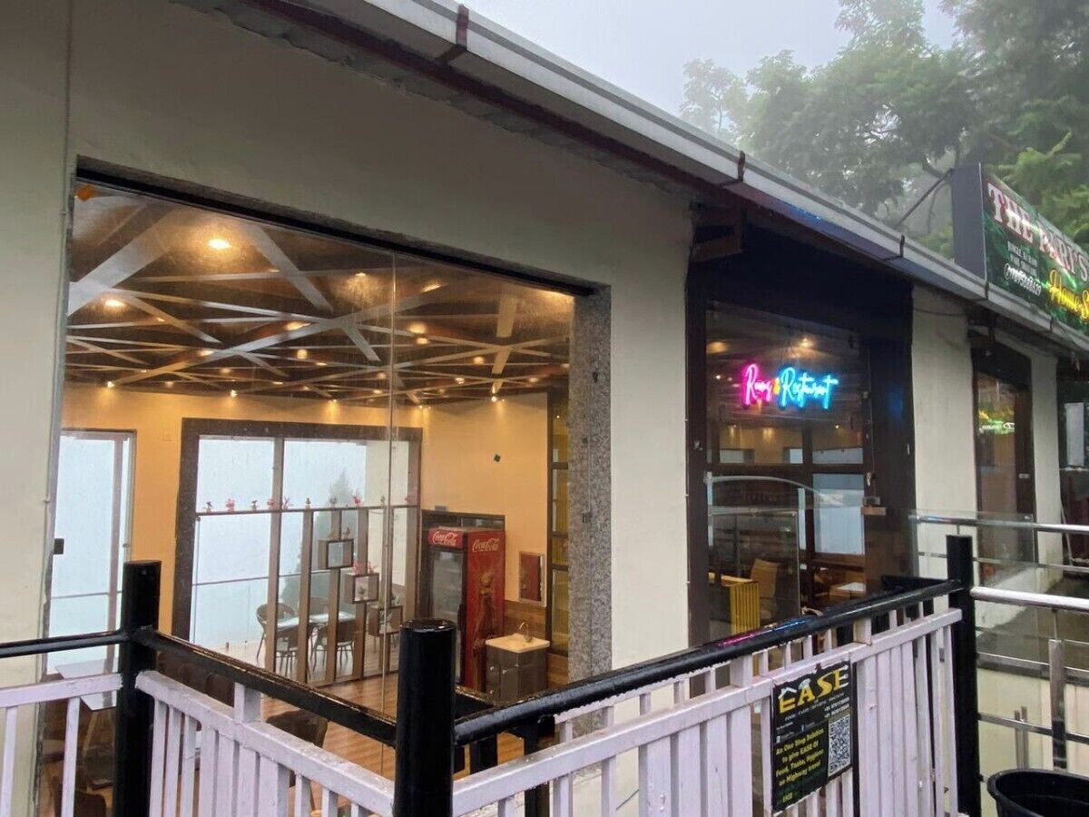 A restaurant with a glass facade, indoor seating, and a Coca-Cola vending machine.