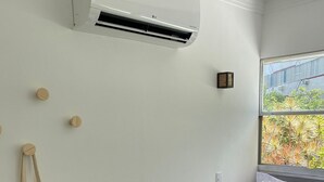 Ein Schlafzimmer mit Bett, Fenster mit Aussicht, Klimaanlage und einem an der Wand befestigten Beutel.