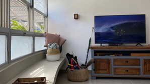 Ein Wohnzimmer mit großem Fenster, Flachbildfernseher, einer Couch, einem Holzschrank und einer Angel.