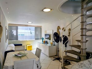 A modern kitchen with a dining area, a staircase, and a view of the outside. - Condomínio Praias do Guarujá - Praia do Tombo - SP (Guarujá)