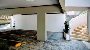 Ein Parkplatz mit Backsteinboden, weißen Wänden und einer weißen Treppe.