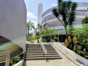 A staircase leading to a building with a curved facade and a cylindrical tower. - Condomínio Praias do Guarujá - Praia do Tombo - SP (Guarujá)