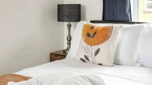 A neatly made bed with white linens, a rolled white towel, and a pillow with a leaf pattern. - Charming 1-BR Apartment near Brick Lane Sleeps 3 (Greater London)