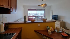 Una cocina con vista al puerto deportivo, armarios de madera, un televisor y un comedor con mesa y sillas.