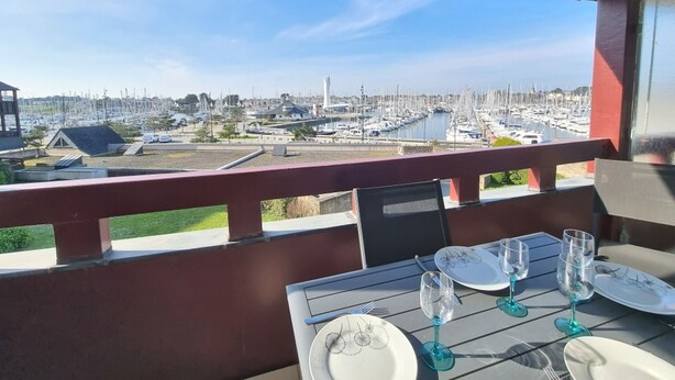 Mesa lista para comer con vistas a un puerto deportivo y al horizonte urbano.