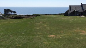 Un campo erboso con una casa e vista sul mare.