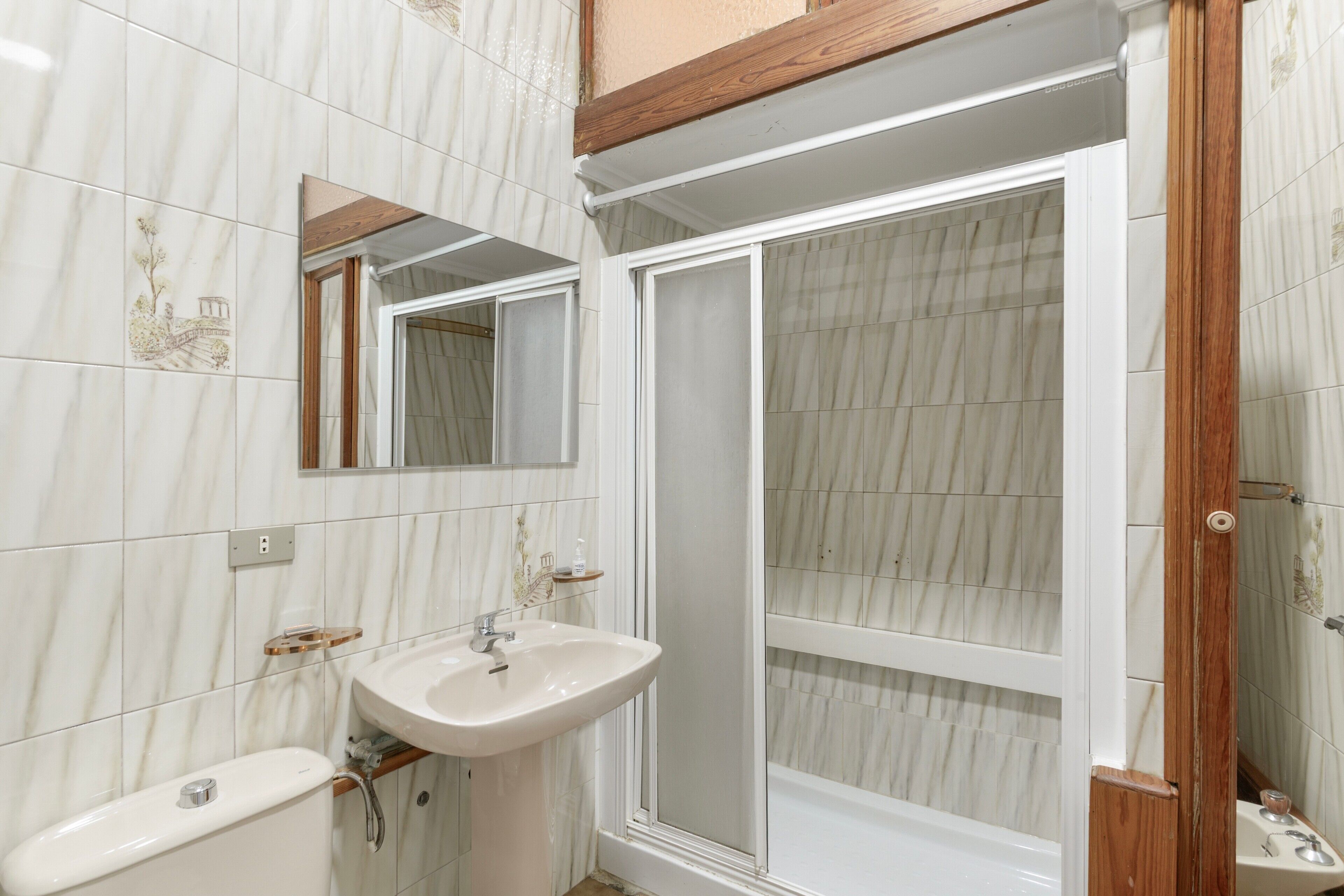 Een badkamer met een wit wastafelmeubel, een spiegel en een douchecabine.