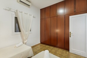 Ein Zimmer mit einem Bett, einem Kleiderschrank, einer Tür und einer Klimaanlage.