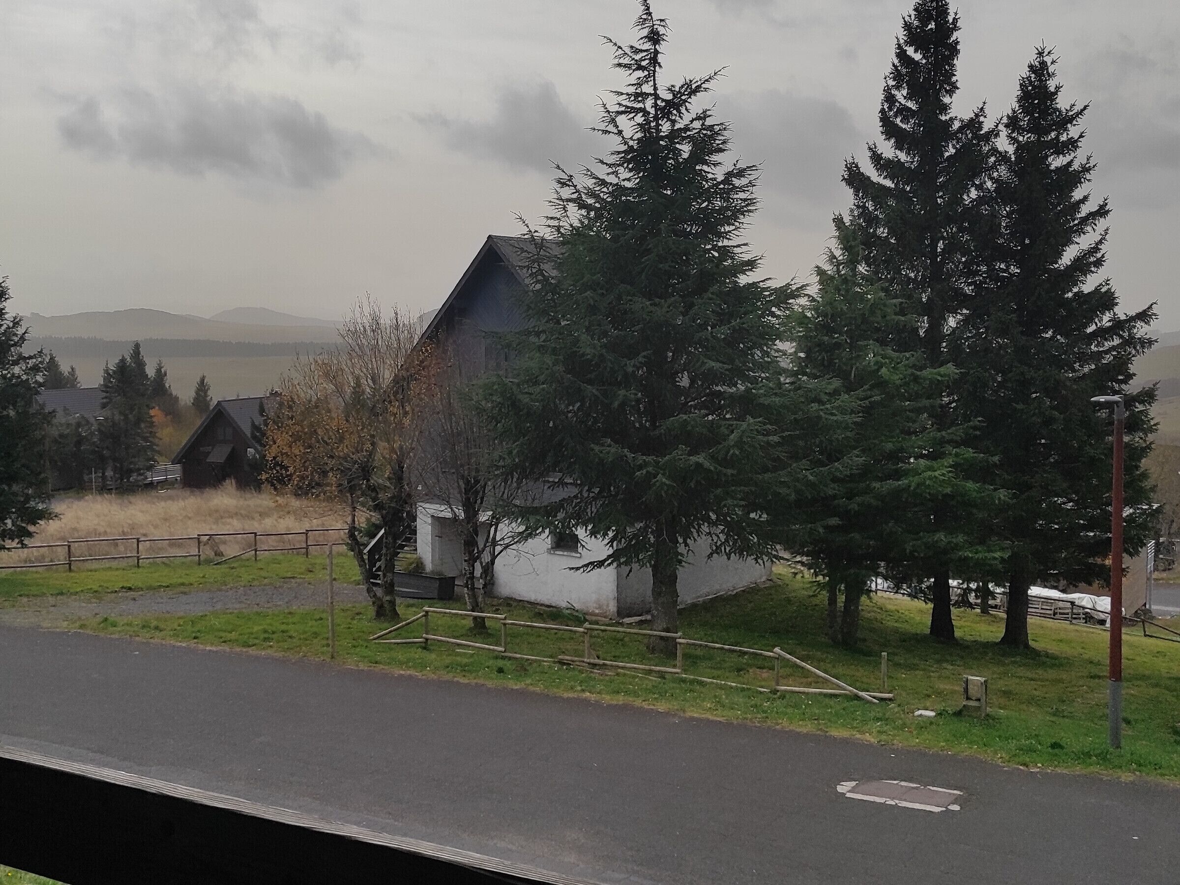 Un paysage rural avec une maison, des arbres et une route.