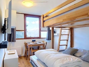 Ein kleines Zimmer mit Stockbetten, einem Schreibtisch und einem Fenster mit Blick.