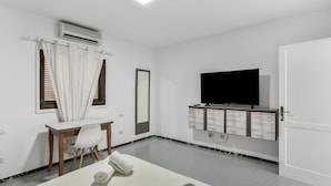 Une chambre d’hôtel comprenant un lit, un bureau avec une chaise, une télévision et une armoire.