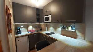 A compact kitchen with dark cabinets, a microwave, a sink, and a small refrigerator. - Studio with Cabin in Valfréjus - Pets Allowed (Valfréjus)